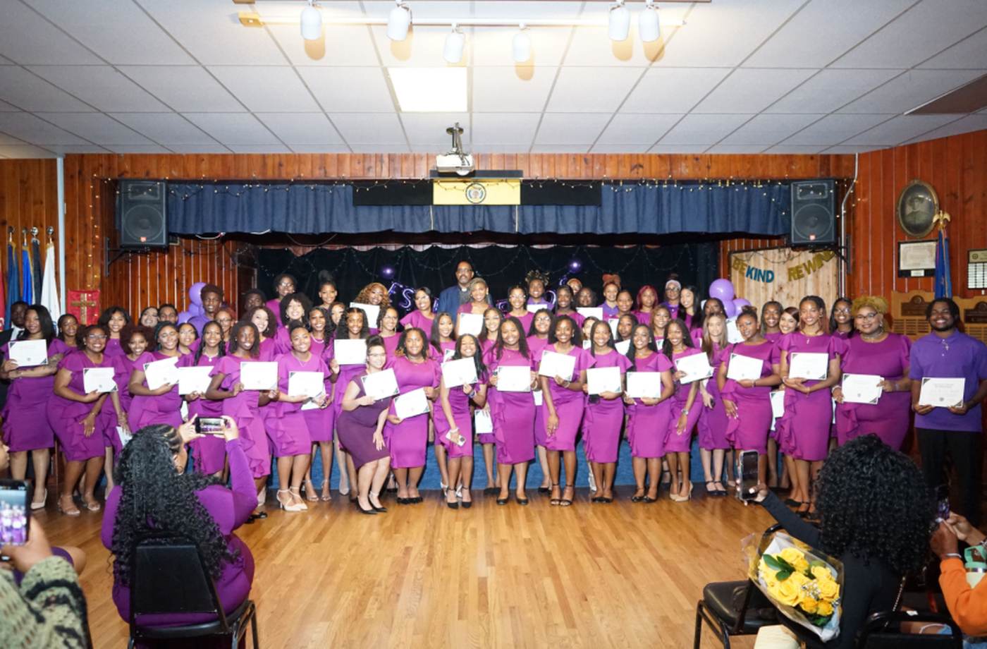 Dozens of women in purple holding certificates at an EFF ceremony